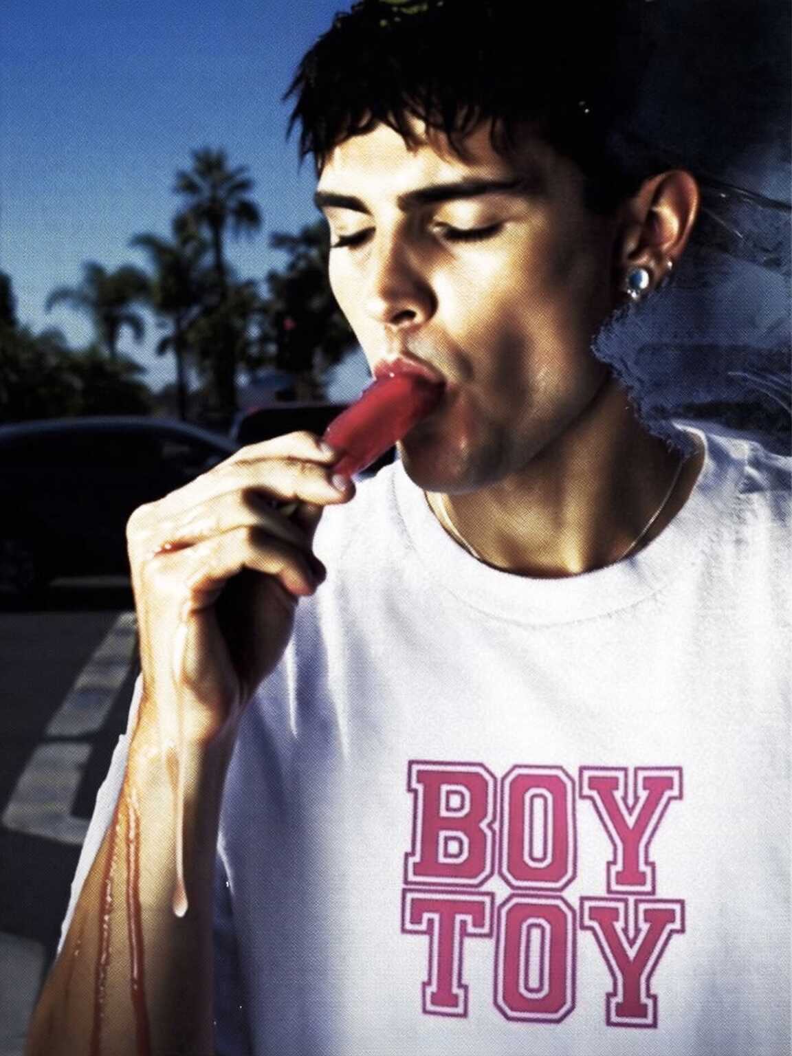 paparazzi-style walking shot of Damon Cael in experimental silhouette coat, rising pop artist Damon Cael.